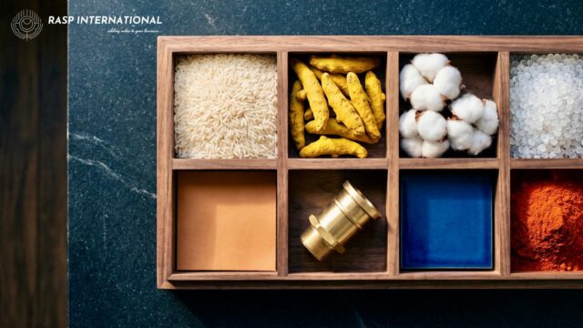 Wooden sample tray holding basmati rice, turmeric, cotton, plastic resin, leather, brass, ceramic tile and spice, showing the export categories covered by RoDTEP